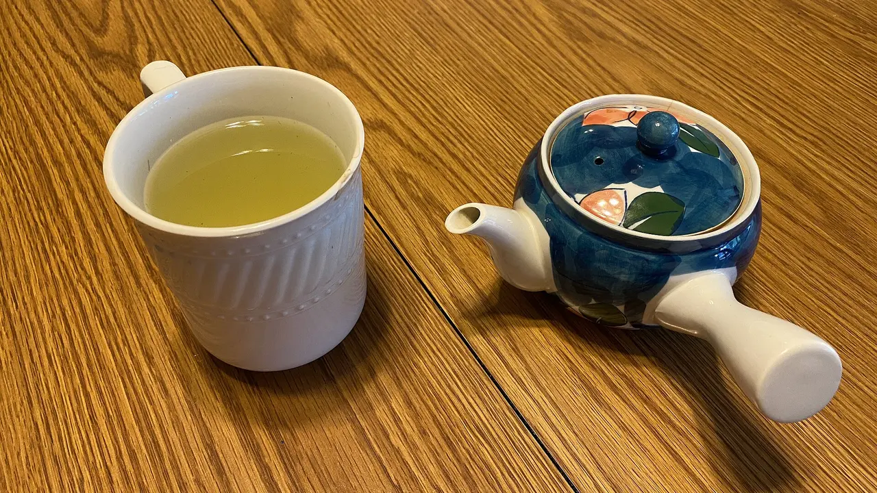 Brewed Japanese green tea in a cup beside a kyusu teapot